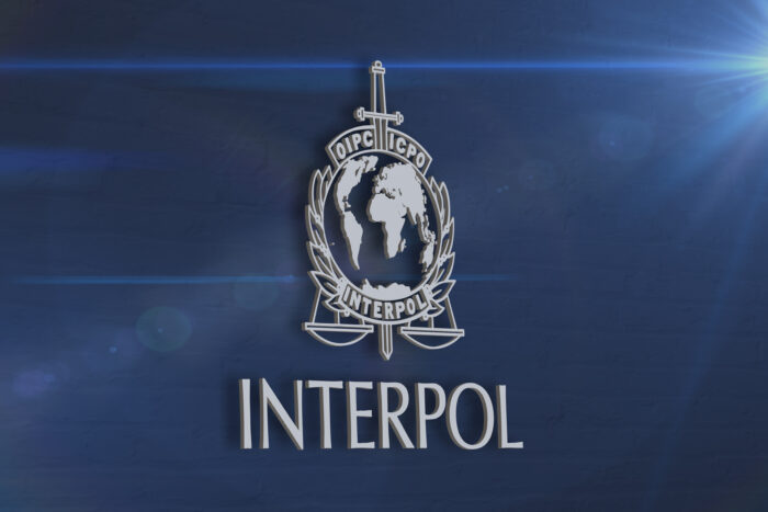 Image of the Interpol sign on a blue wall background Image of the Interpol sign on a blue wall background
