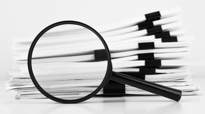 AG Annual Report Magnifying glass inspecting a stack of papers